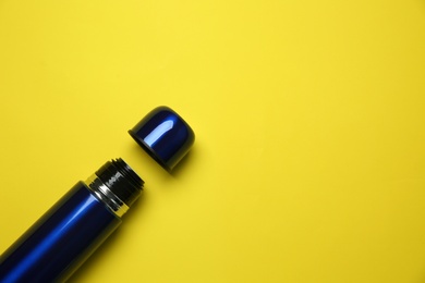 New modern thermos and cup on yellow background, flat lay. Space for text