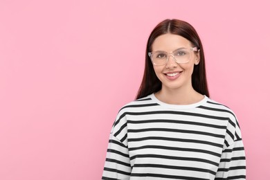 Smiling woman in stylish eyeglasses on pink background. Space for text