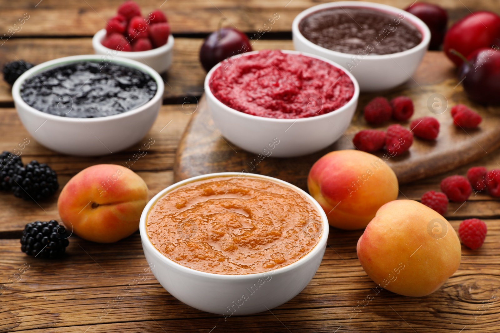 Photo of Different puree in bowls and fresh fruits on wooden table