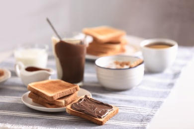 Photo of Delicious breakfast with toasts and chocolate paste on table