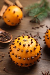 Photo of Pomander balls made of tangerines with cloves on wooden table