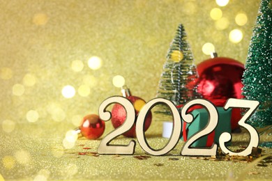 Photo of Number 2023 and festive decor on bright background, bokeh effect. Happy New Year