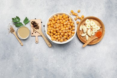 Photo of Delicious chickpeas and different ingredients on light grey table, flat lay with space for text. Cooking hummus