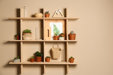 Photo of Wooden shelves with different decorative elements on beige wall, space for text