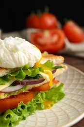 Tasty sandwich with poached egg on plate, closeup