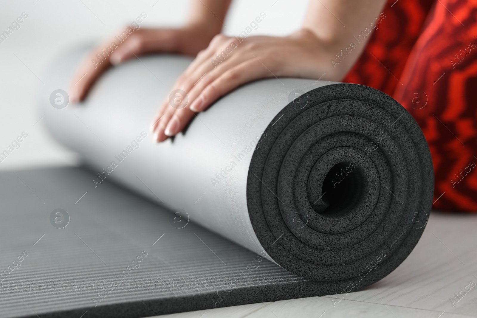 Photo of Young woman rolling yoga mat, closeup of hands