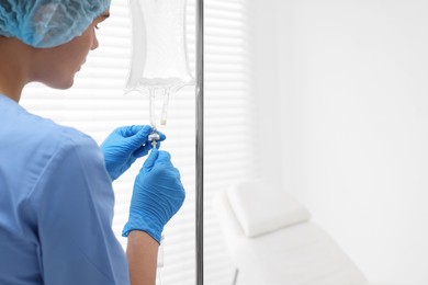 Nurse setting up IV drip in hospital, closeup. Space for text