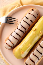 Different tasty glazed eclairs served on table, top view