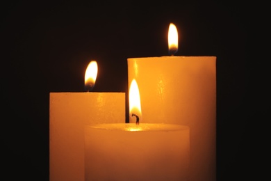 Photo of Burning candles on dark background. Symbol of sorrow