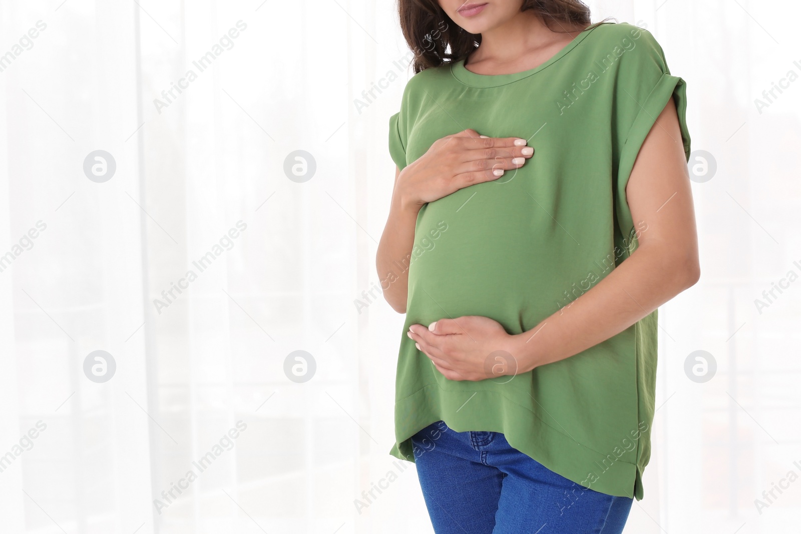 Photo of Beautiful pregnant woman near window at home