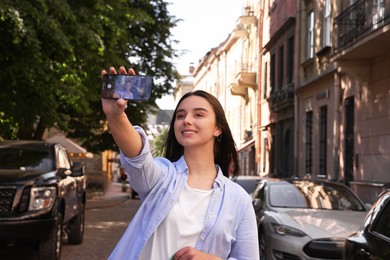 Travel blogger with smartphone recording video on city street