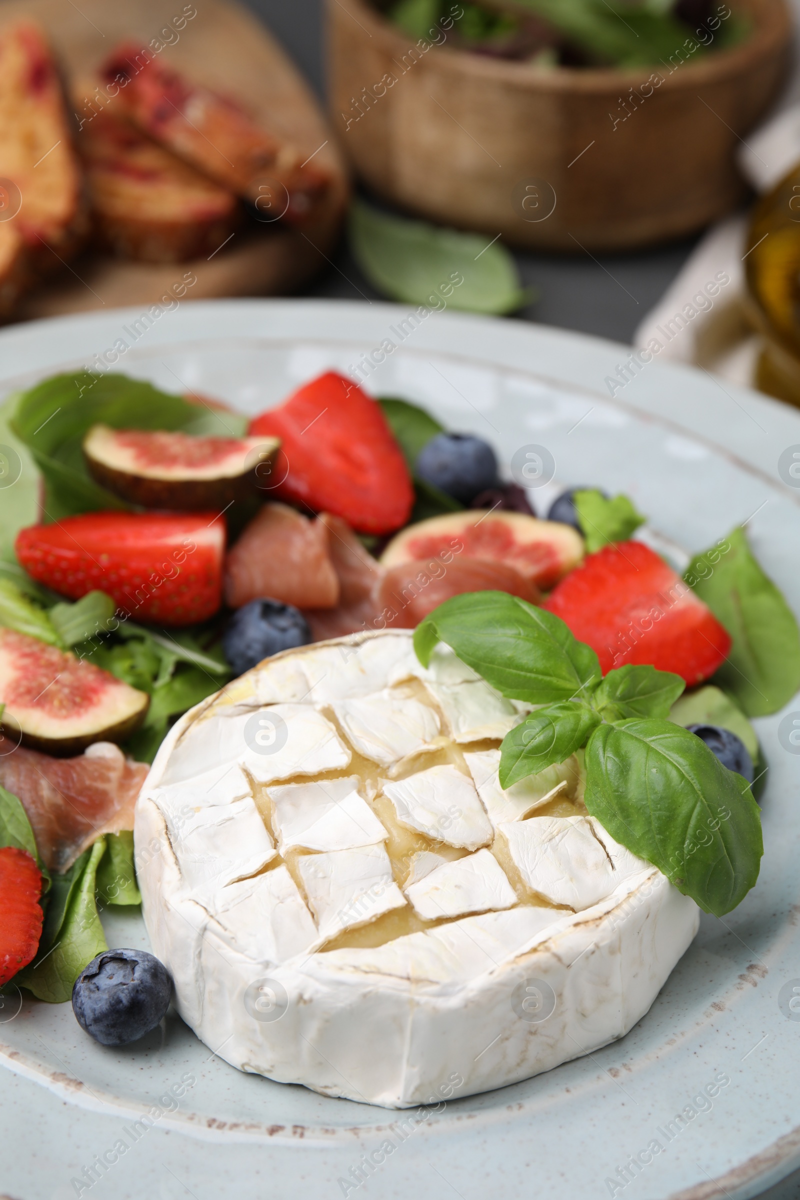 Photo of Delicious salad with brie cheese, blueberries, figs and strawberries on plate, closeup