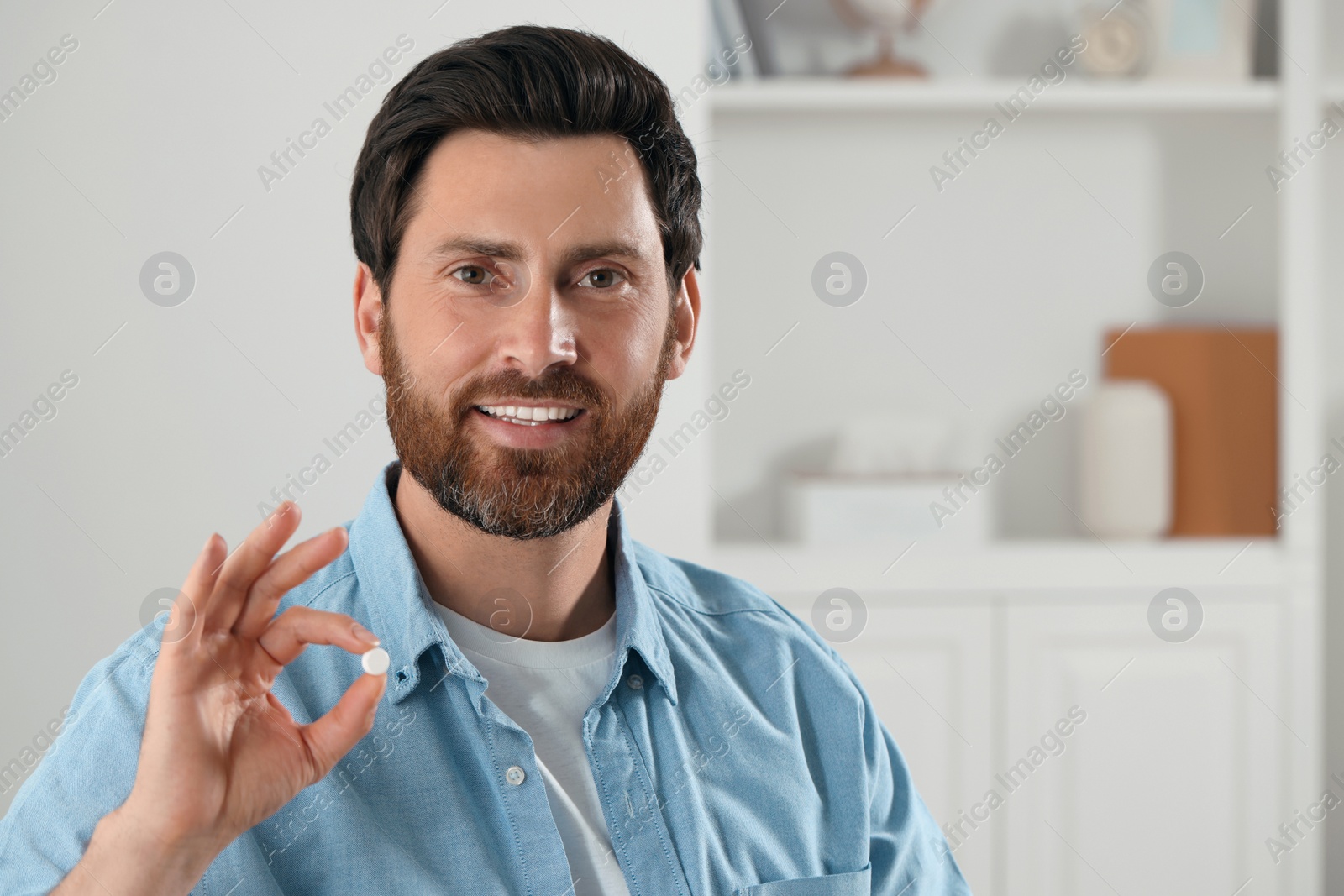 Photo of Portrait of happy man with pill at home, space for text