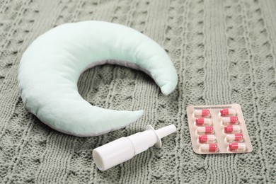 Photo of Pillow, pills and nasal spray on blanket, closeup
