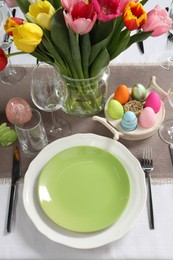 Photo of Easter celebration. Festive table setting with beautiful flowers and painted eggs, above view