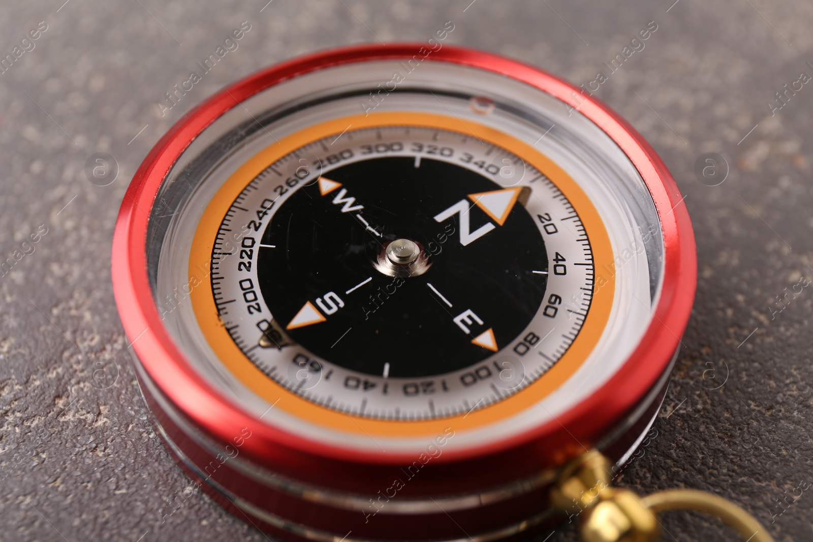 Photo of One compass on grey textured background, closeup. Navigation equipment