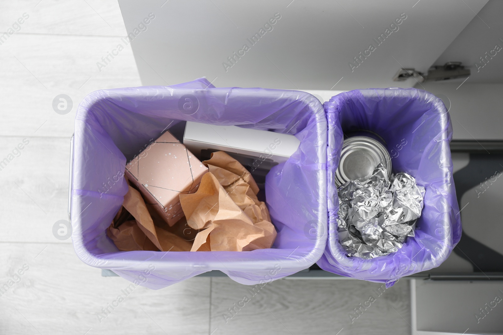 Photo of Open cabinet with full trash bins for separate waste collection in kitchen, top view