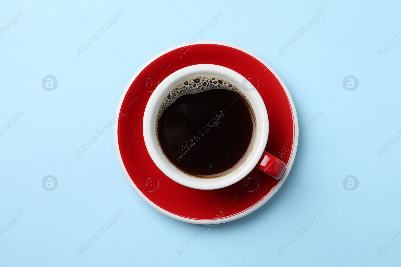 Photo of Aromatic coffee in cup on light blue background, top view