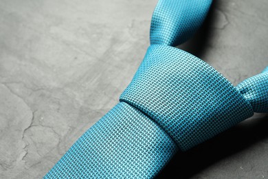 Photo of One light blue necktie on grey textured table, closeup