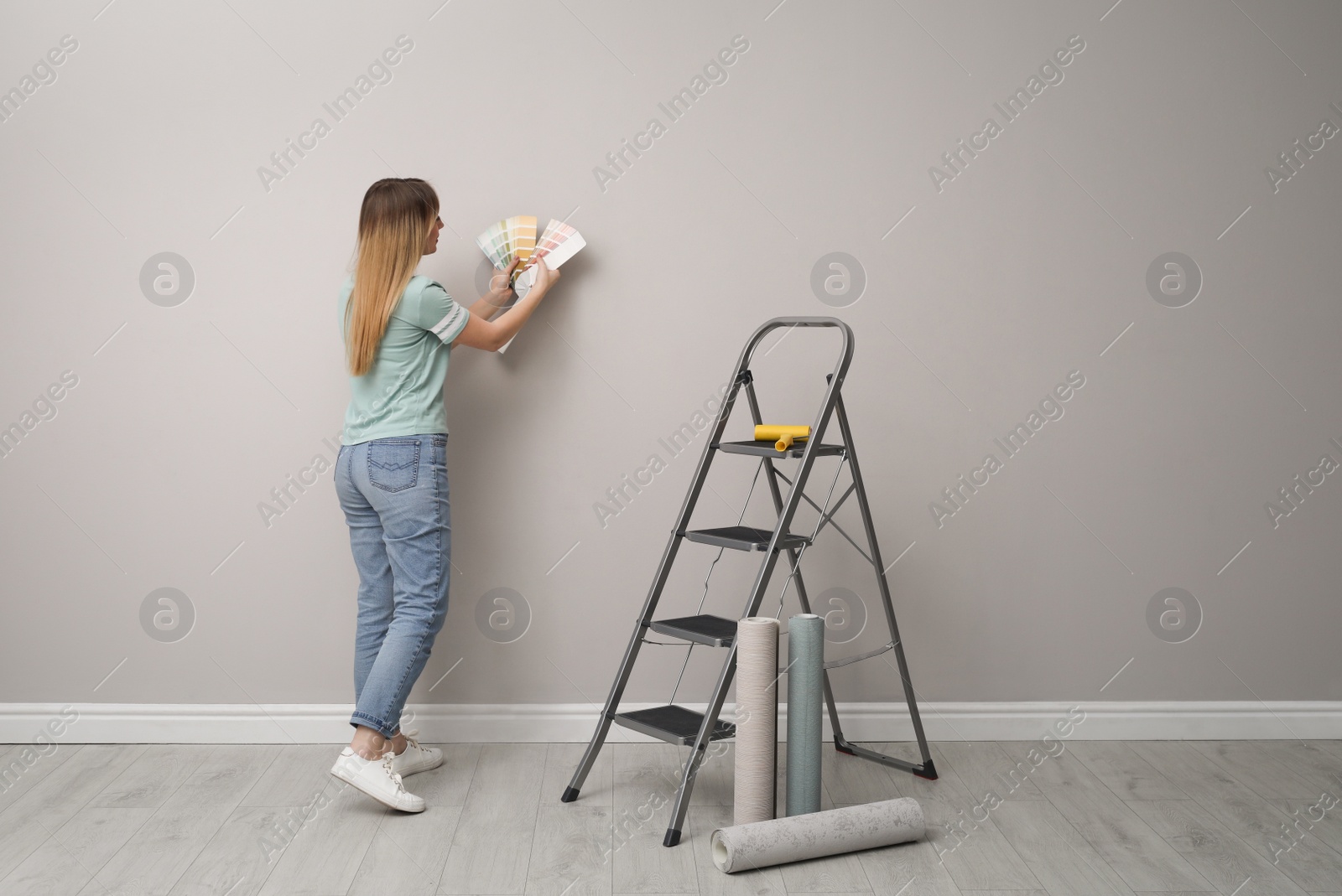 Photo of Woman with palette choosing wall paper color indoors