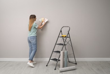 Photo of Woman with palette choosing wall paper color indoors
