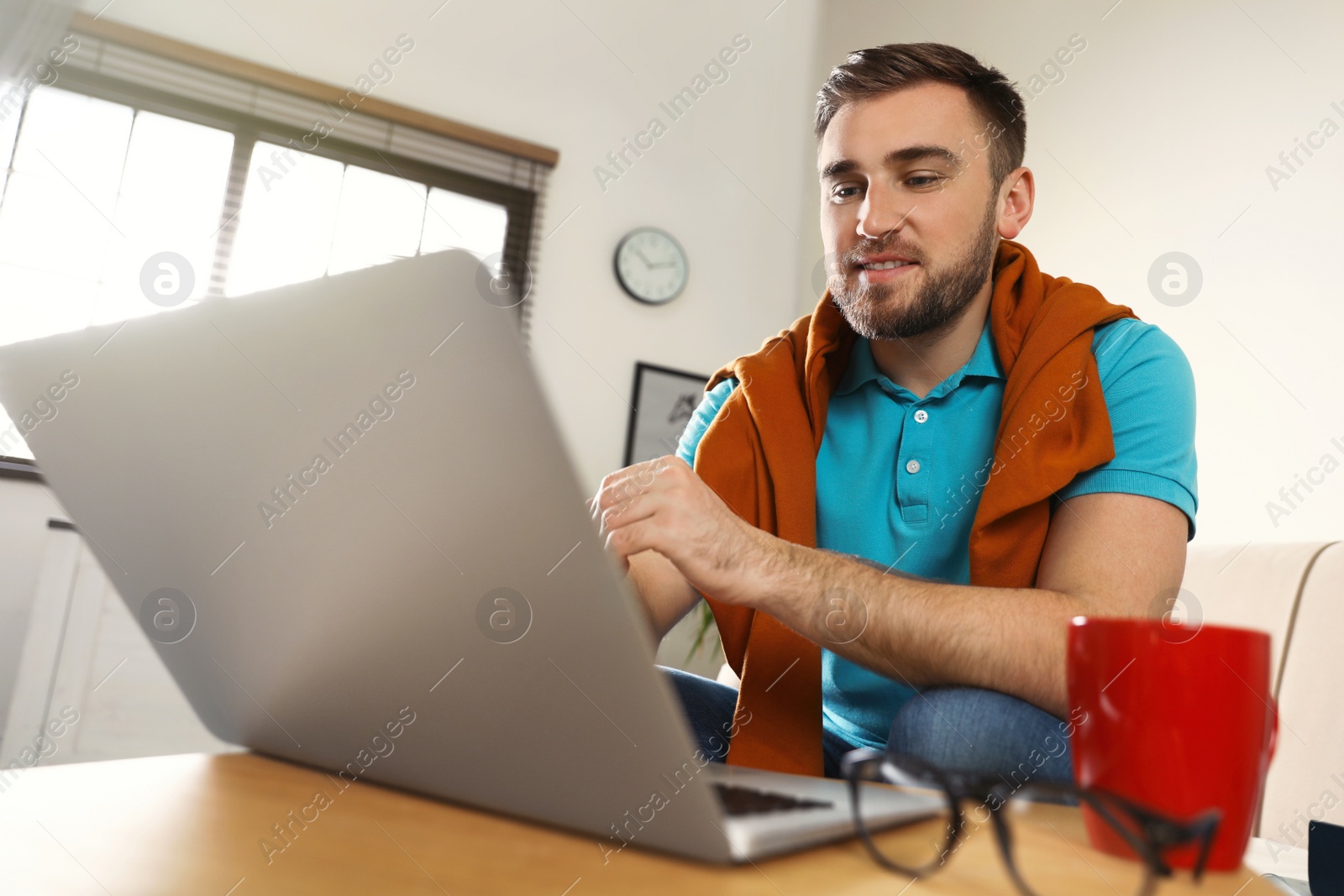 Photo of Young man using laptop at table indoors