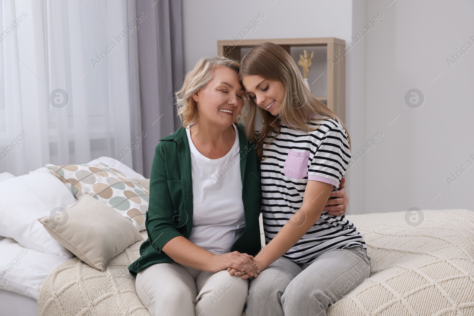 Photo of Young woman with her mom on bed at home. Happy Mother's Day