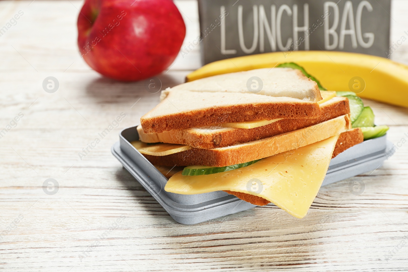 Photo of Lunch box with tasty sandwich on wooden table