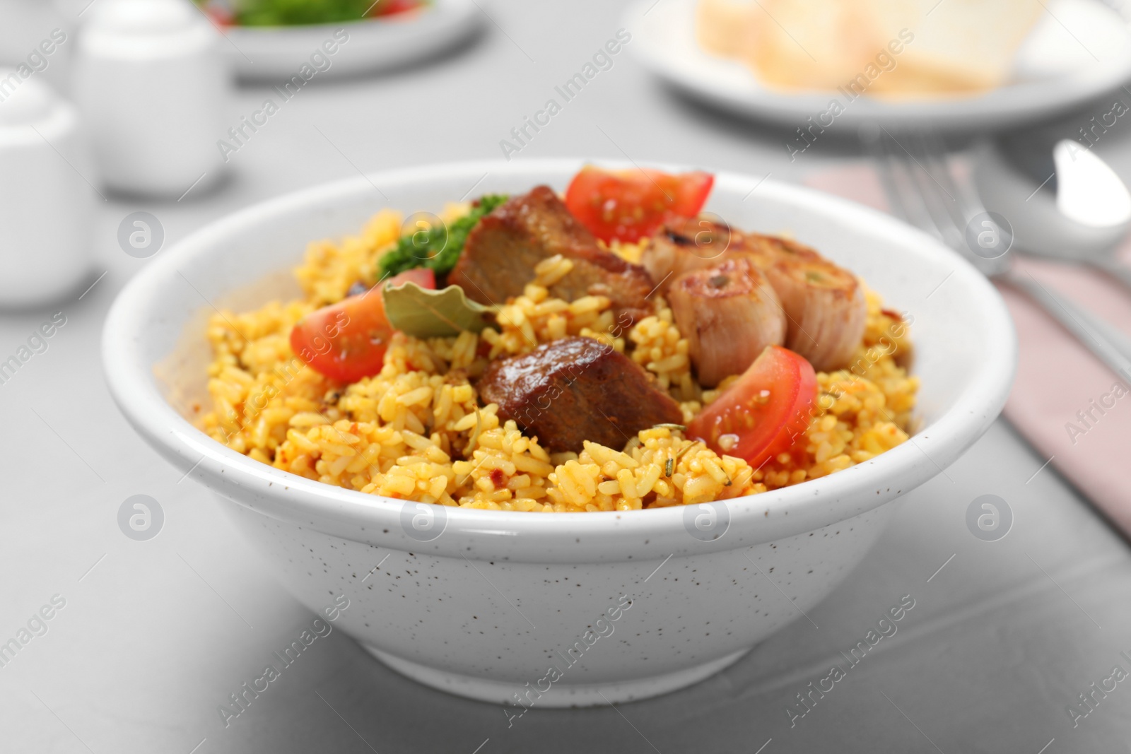 Photo of Bowl of tasty rice pilaf with meat on table