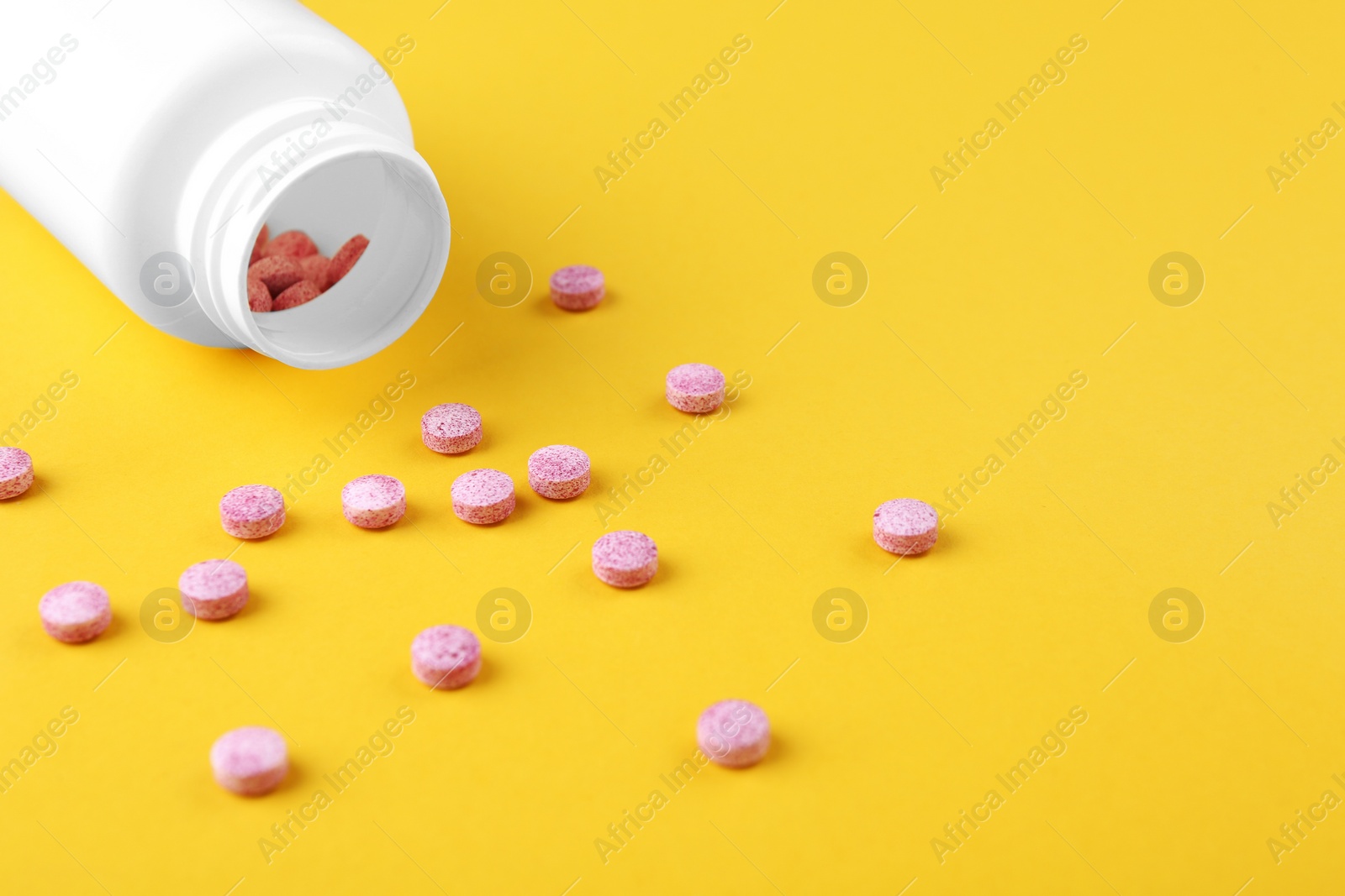 Photo of Bottle and vitamin pills on yellow background, closeup. Space for text