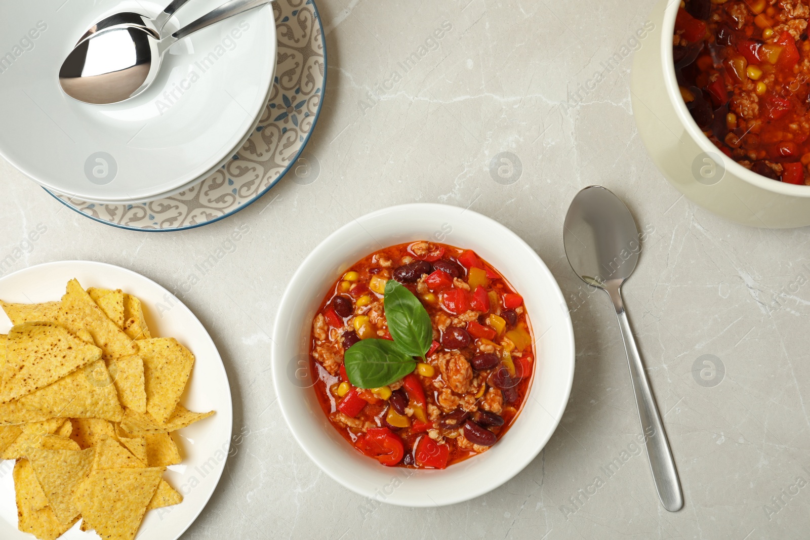 Photo of Flat lay composition with chili con carne and tortilla chips on light background