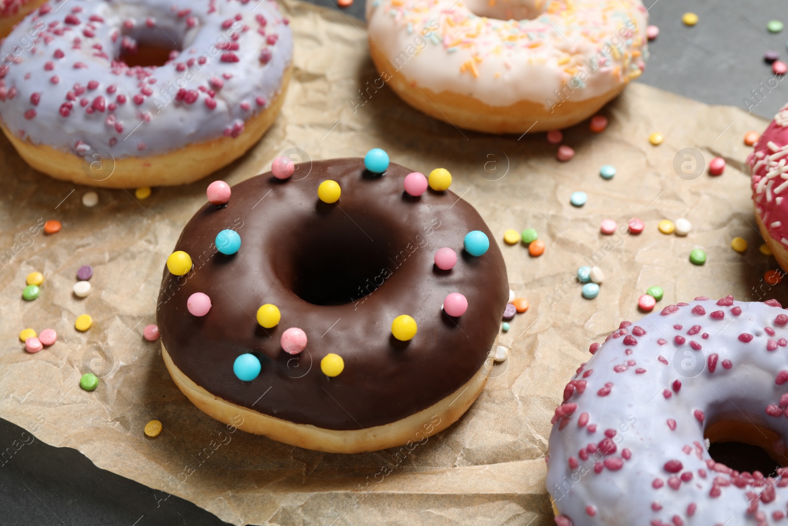 Photo of Yummy donuts with sprinkles on dark background, closeup