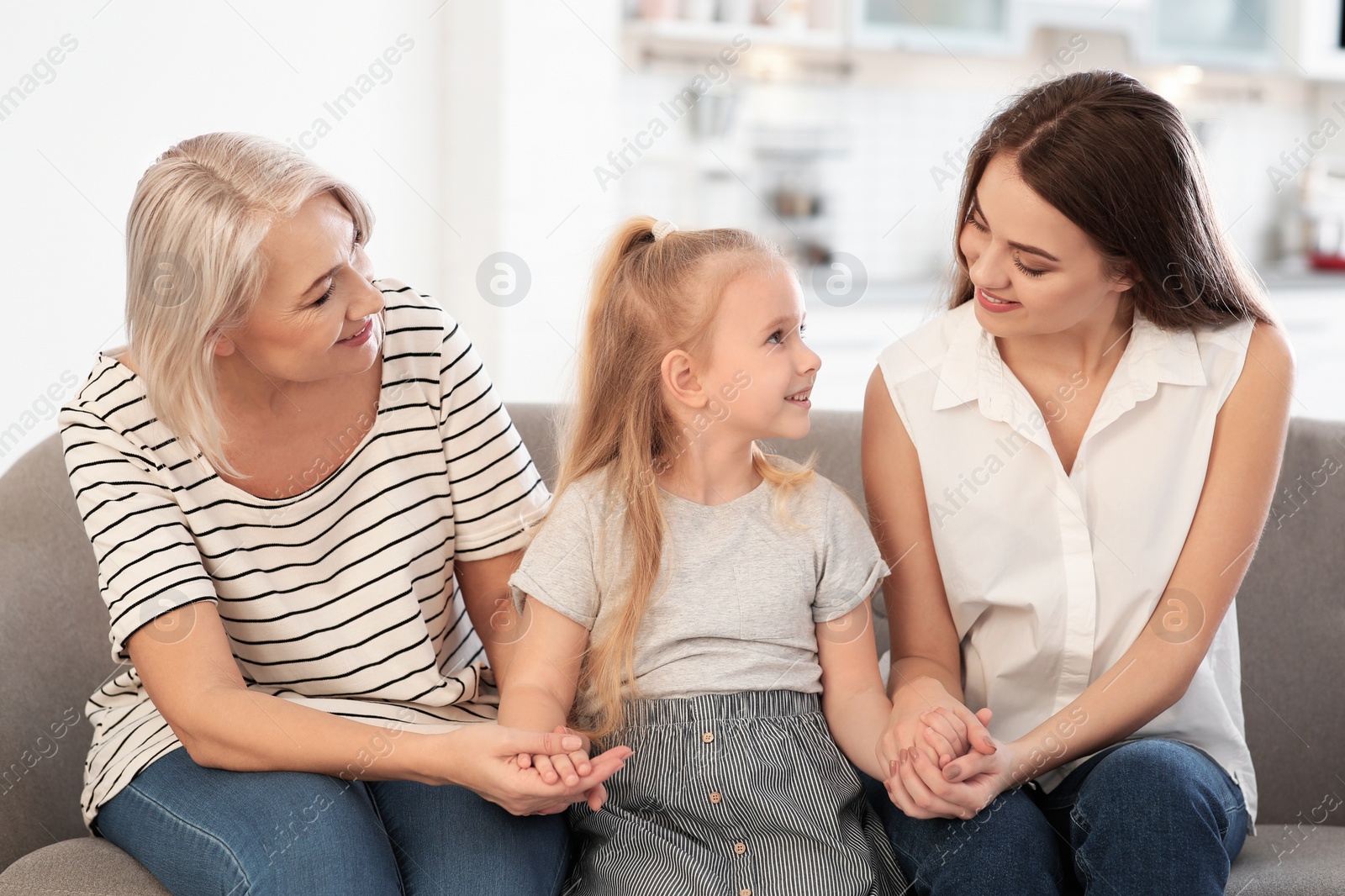 Photo of Portrait of young woman, her mature mother and daughter on sofa in living room