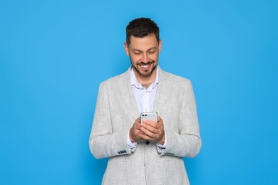 Photo of Happy man with smartphone on light blue background