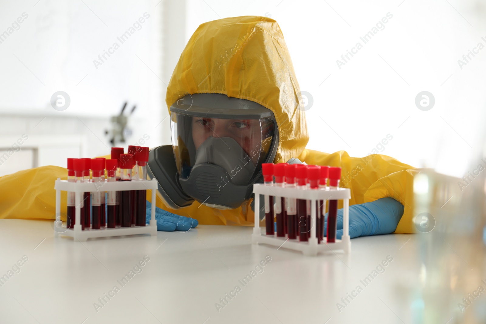 Photo of Scientist in chemical protective suit working with blood samples at laboratory. Virus research