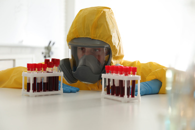 Photo of Scientist in chemical protective suit working with blood samples at laboratory. Virus research