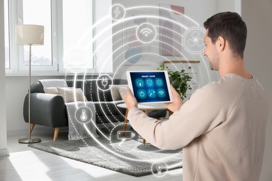 Image of Man using smart home control system via application on tablet indoors. Scheme with icons around device