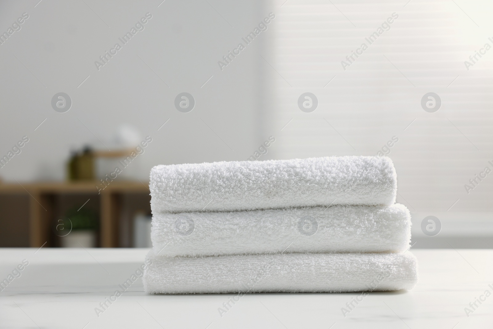 Photo of Stacked bath towels on white table indoors