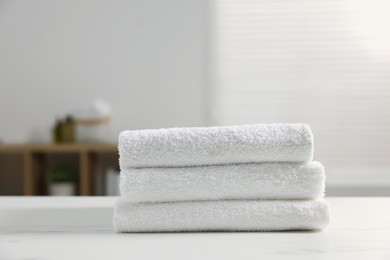 Photo of Stacked bath towels on white table indoors