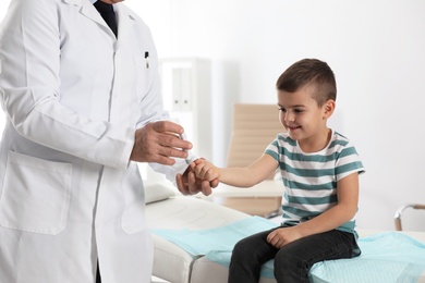 Photo of Little patient and doctor with lancet pen in hospital. Diabetes control