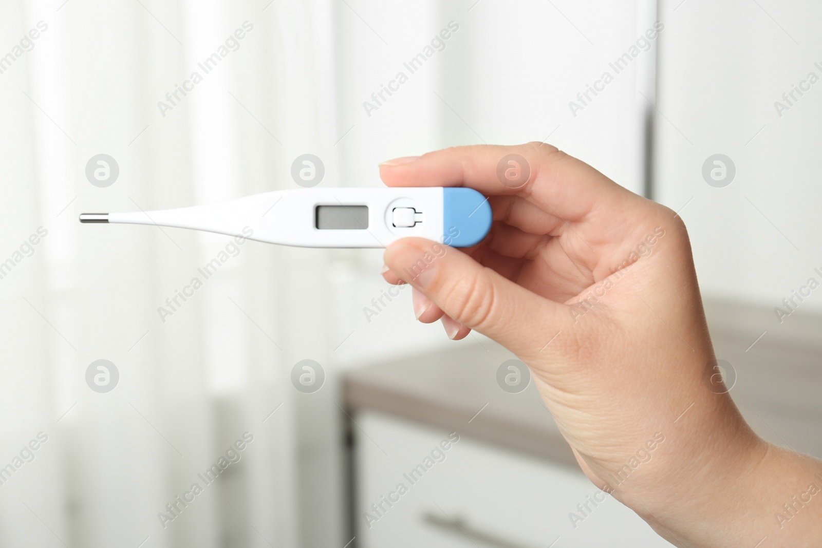 Photo of Woman with modern digital thermometer indoors, closeup