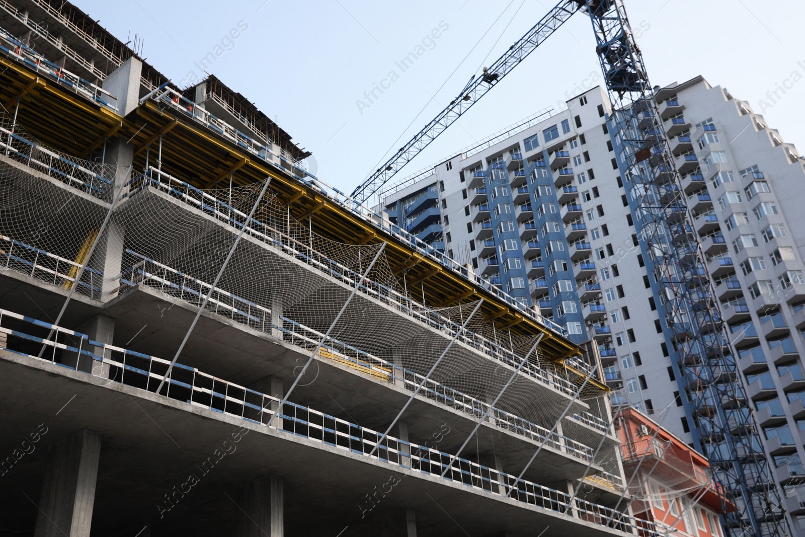 Photo of Construction site with tower crane near unfinished building, low angle view