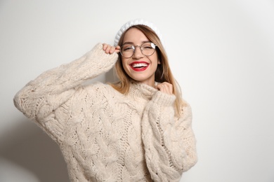 Beautiful young woman in warm sweater with hat on white background