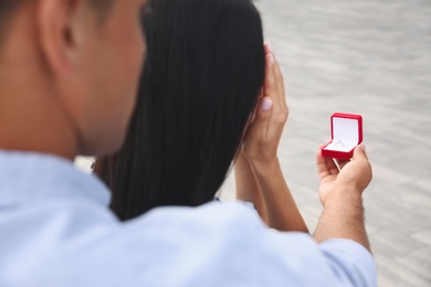 Man with engagement ring making proposal to his girlfriend outdoors, closeup