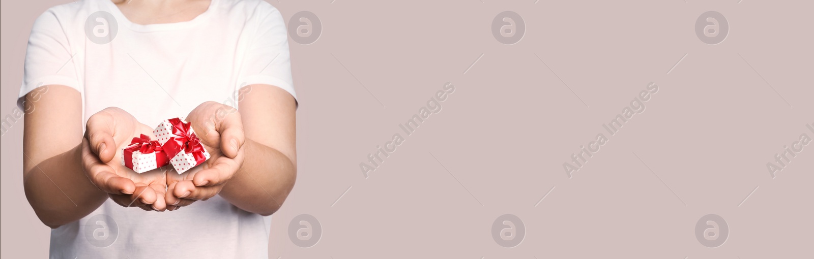 Image of Boxing day, banner design. Woman with gifts on beige background, closeup and space for text