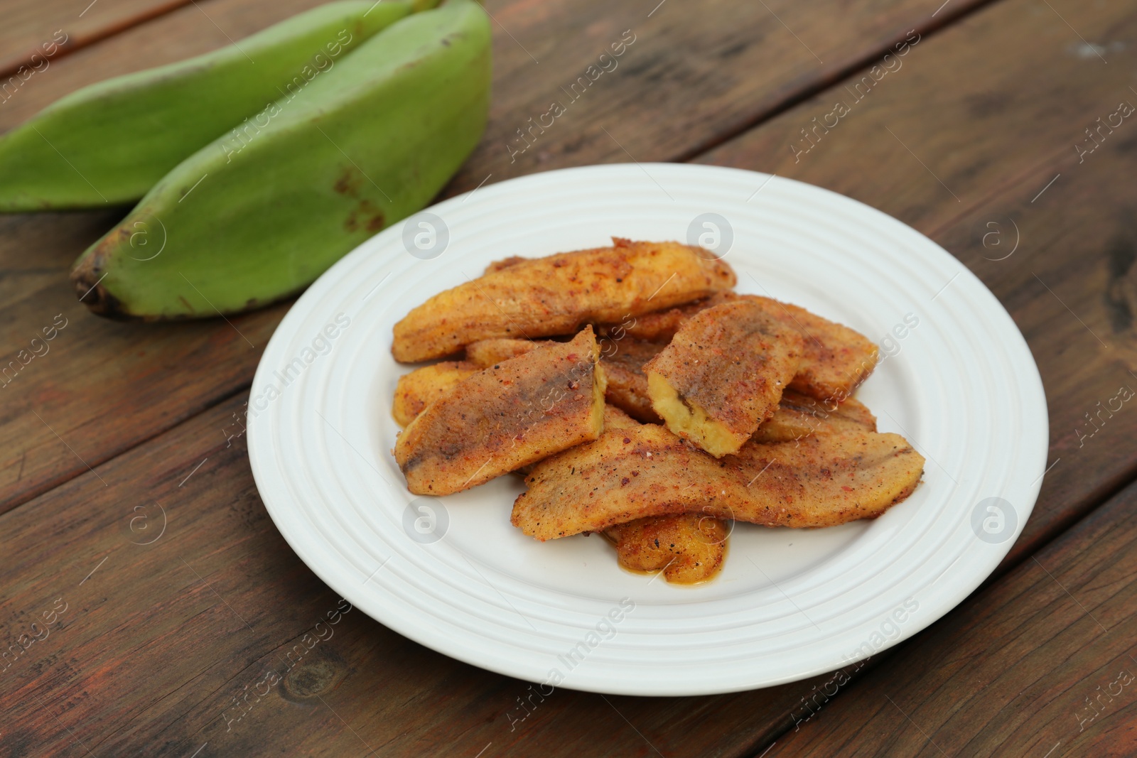 Photo of Delicious fried bananas and fresh fruits on wooden table