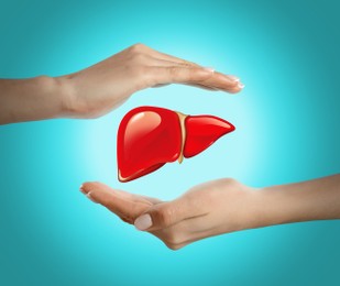 Image of Woman holding hands around illustration of liver on turquoise background, closeup