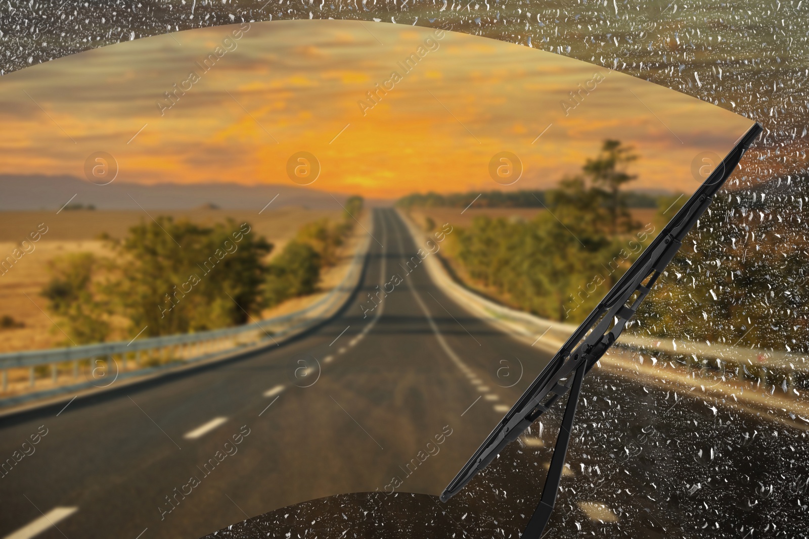 Image of Car windshield wiper cleaning water drops from glass while driving