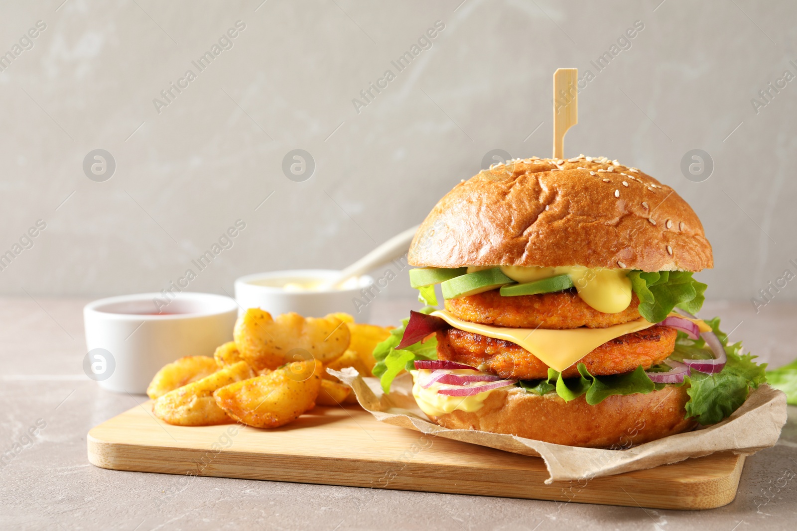Photo of Board with double vegetarian burger and fried potatoes on table