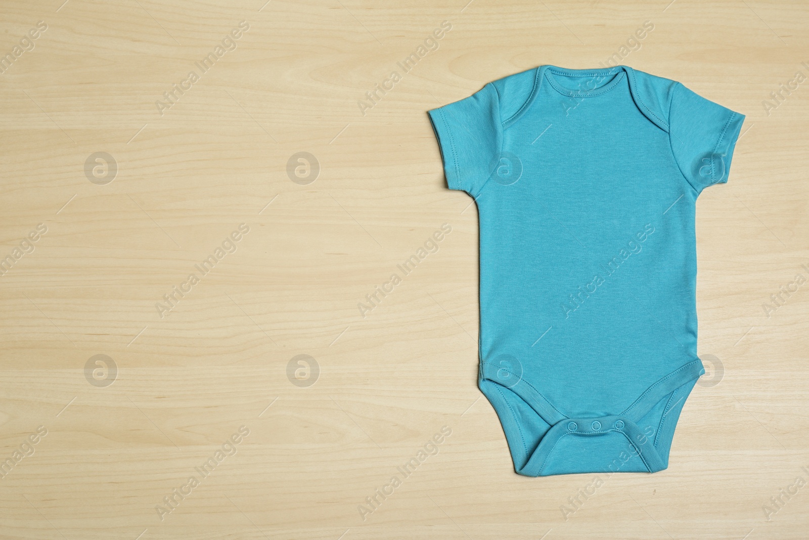 Photo of Cute baby onesie on wooden background, top view. Space for text